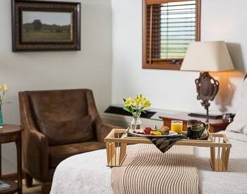 Tray with Breakfast on it sitting at the foot of the bed, one brown sitting chair